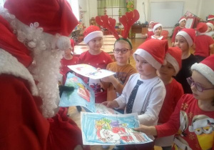 dzieci z gr V wręczają Mikołajowi swoje ilustracje